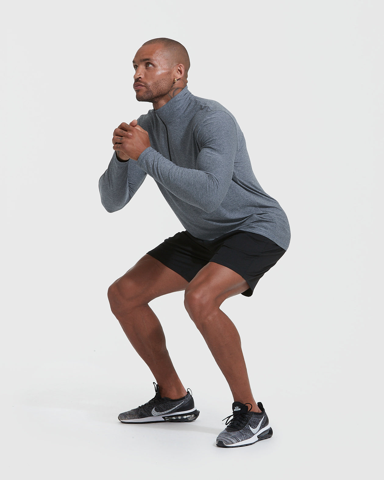 Man squatting in Heather Navy Active Quarter Zip Shirt.