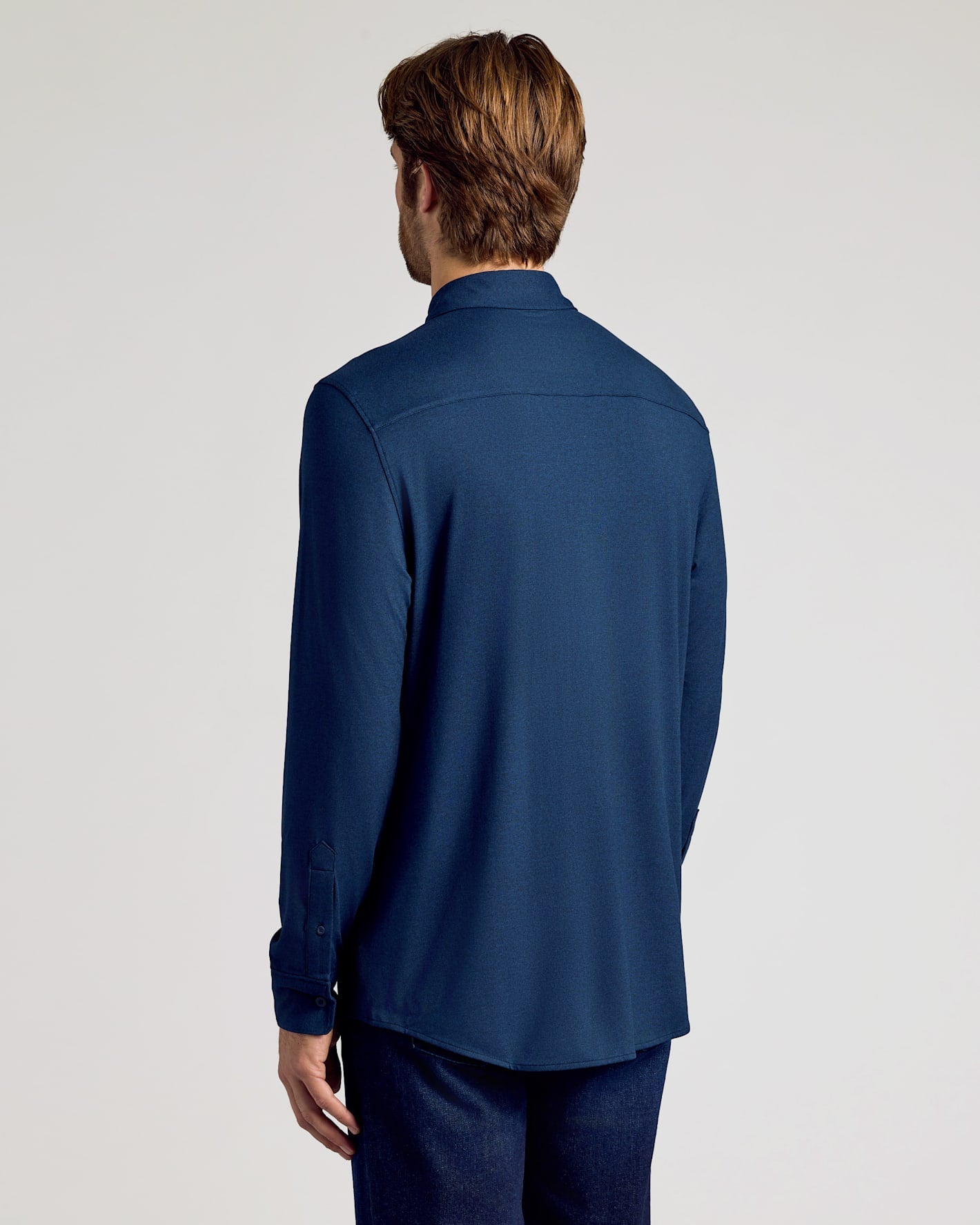 Man wearing a blue shirt from behind on a light gray background