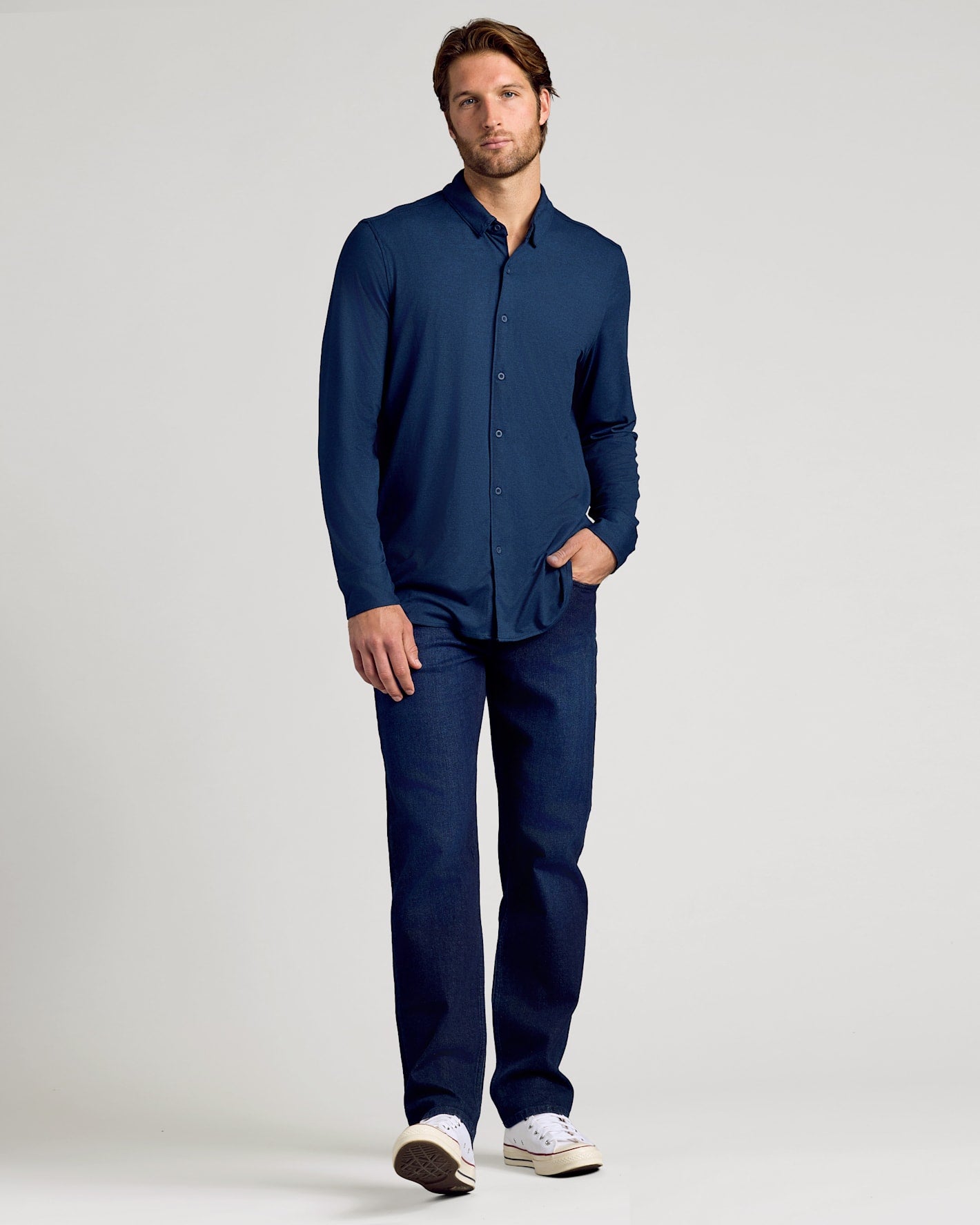 Man wearing a navy blue shirt and pants on a light gray background