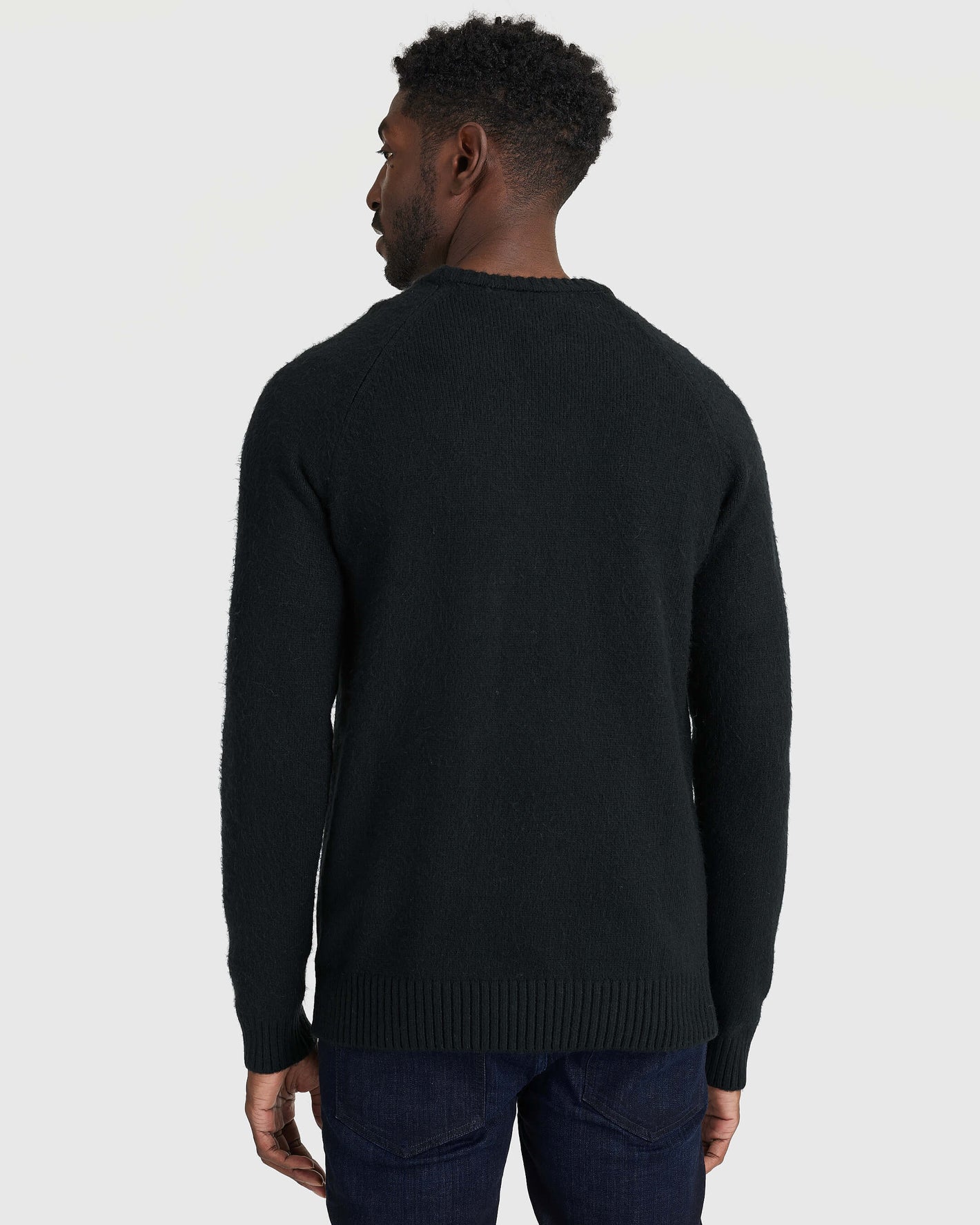 Black Crew Neck Sweater with ribbed cuffs, paired with dark jeans.