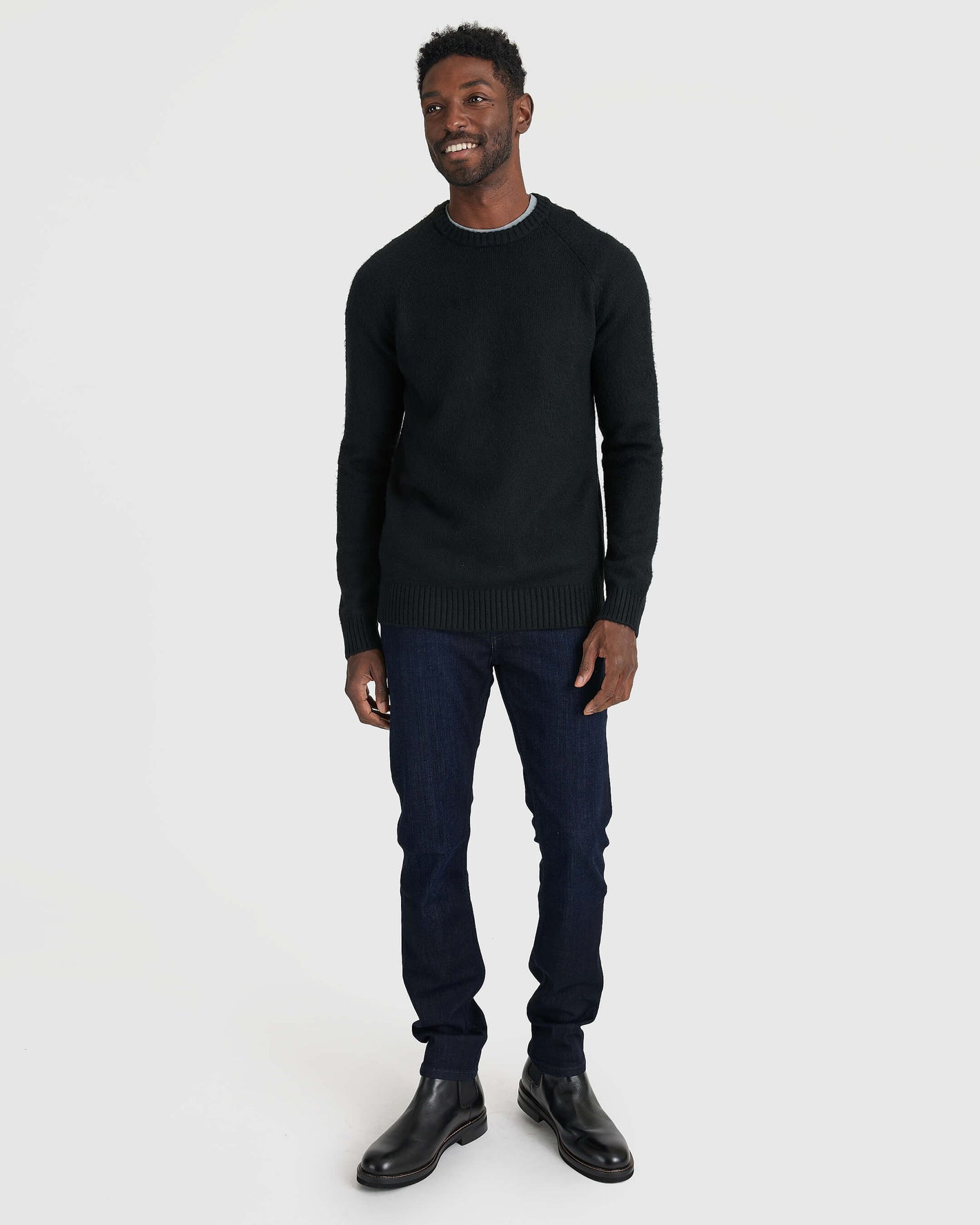 Man in Black Crew Neck Sweater, jeans, and Chelsea boots.