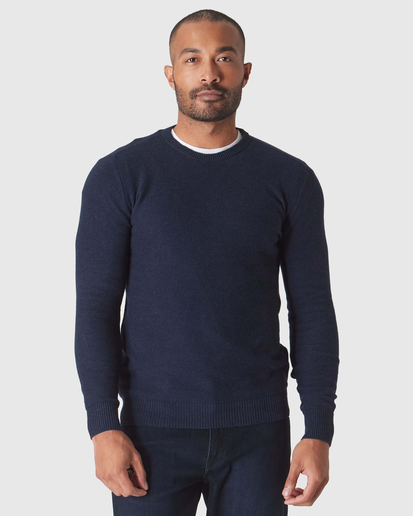 Man wearing Heather Navy Pique Crew Sweater over white T-shirt.