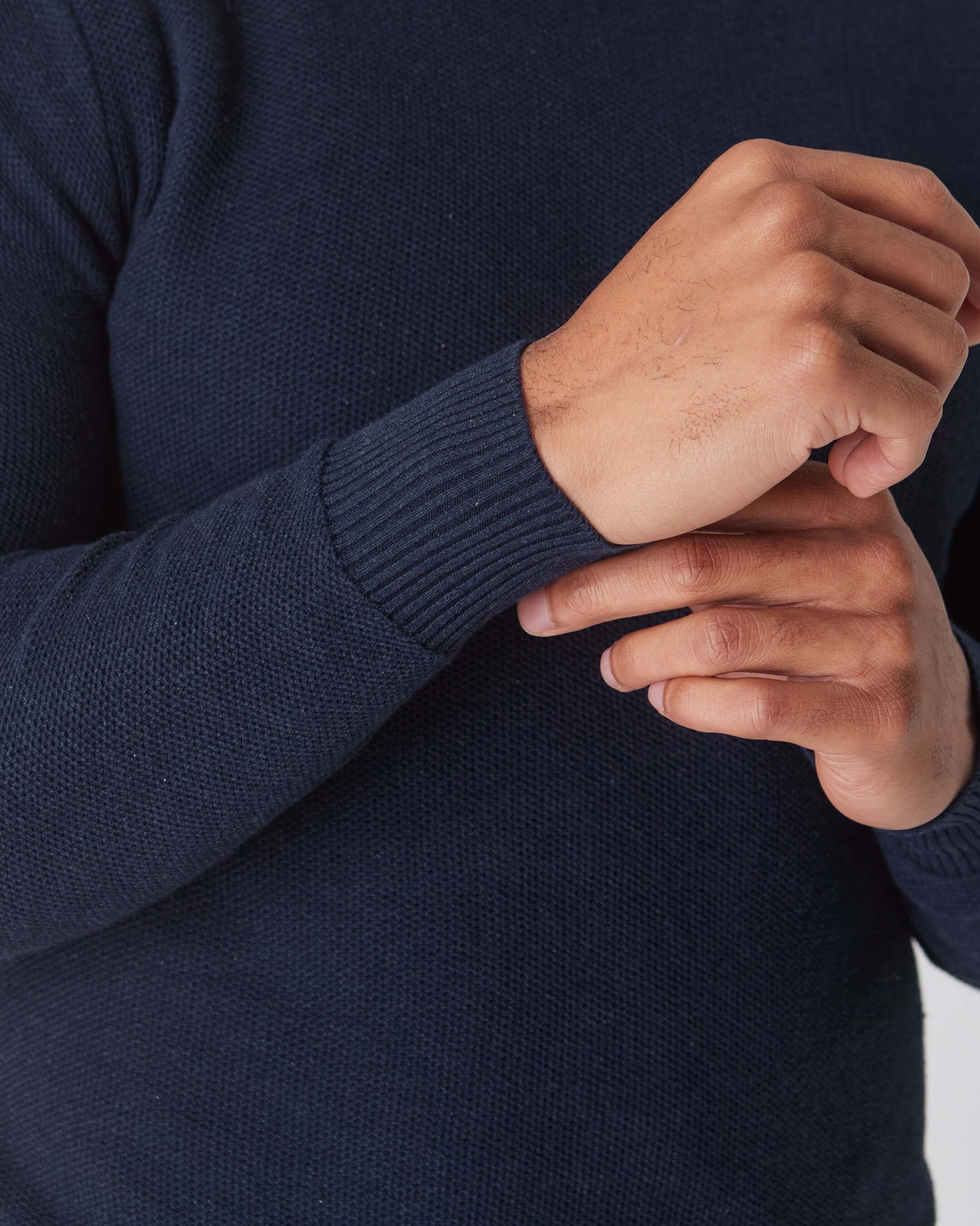 Heather Navy Pique Crew Sweater with textured fabric, hand adjusting sleeve.