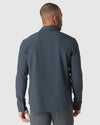 Man models Heather Navy Long Sleeve Ripstop Commuter Shirt from the back.