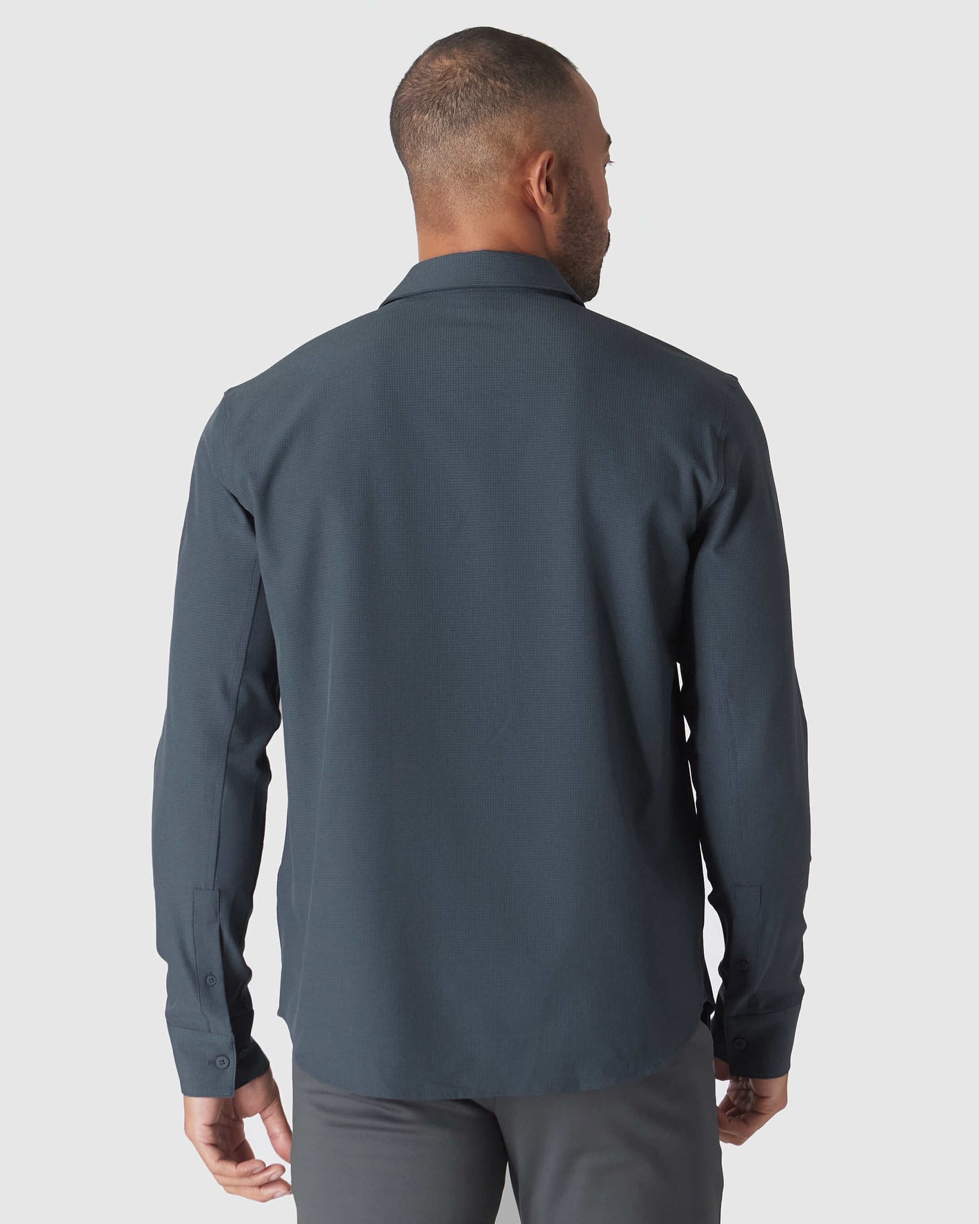 Man models Heather Navy Long Sleeve Ripstop Commuter Shirt from the back.