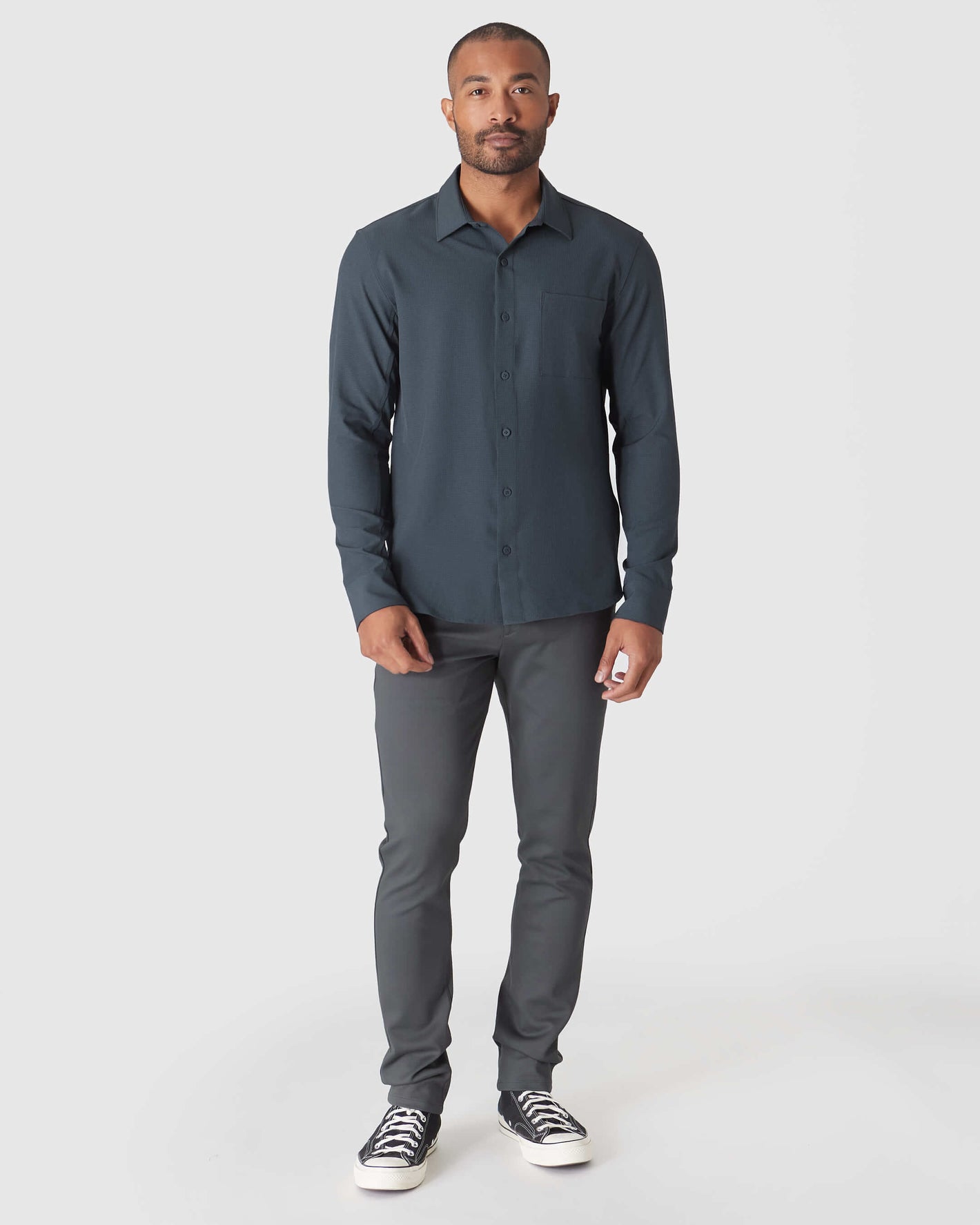 Model in Heather Navy Long Sleeve Ripstop Commuter Shirt and charcoal trousers.