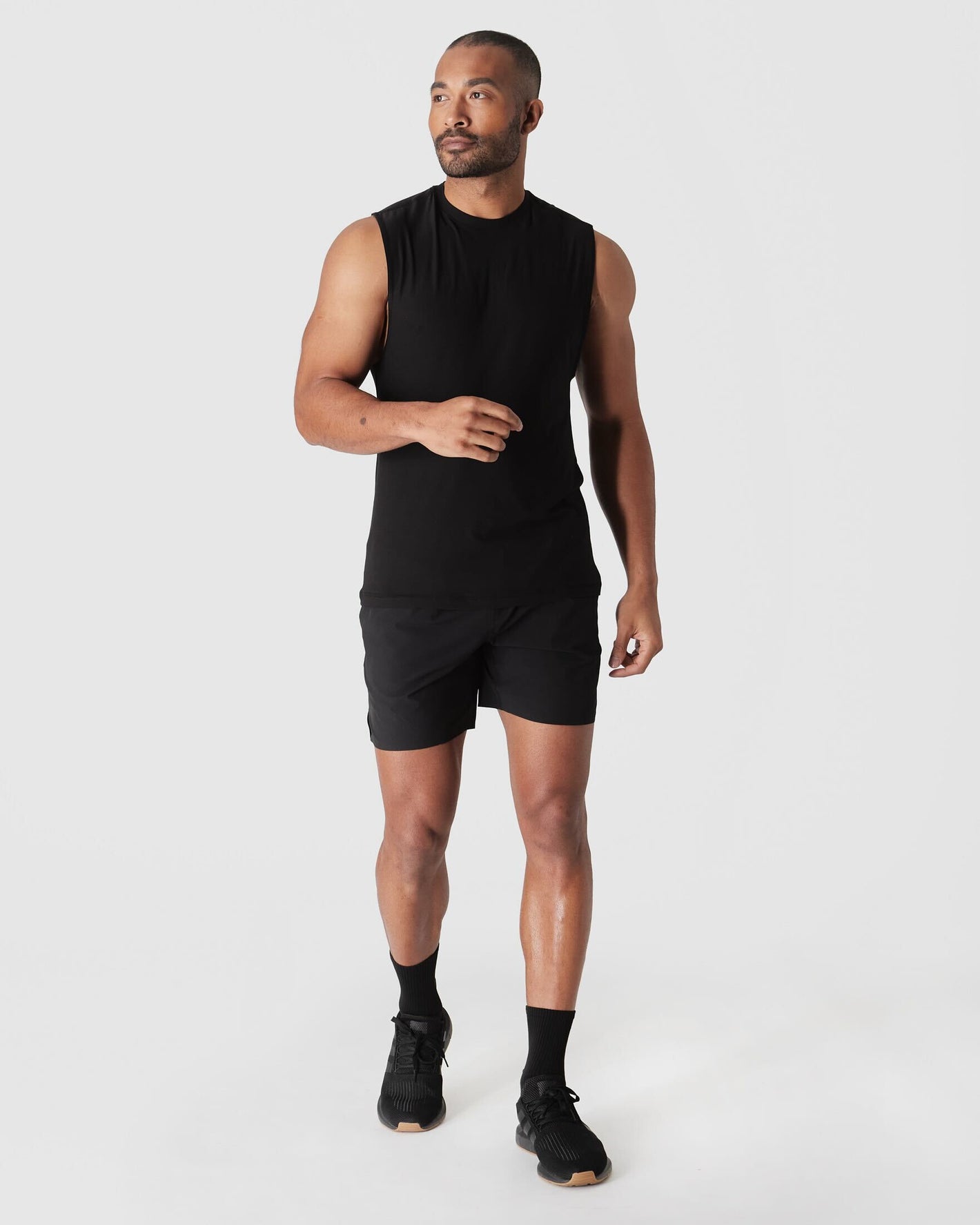 Man wearing Black Active Sleeveless Muscle Tee, mid-stride, showcasing athletic fit.