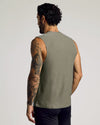 A man with tattoos on his left arm wearing a Heather Military Green Sleeveless Active Muscle Tee, shown from the back, highlighting the fitted sleeveless design and soft fabric.