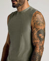 Close-up of a man wearing a Heather Military Green Sleeveless Active Muscle Tee, showcasing the soft fabric and detailed tattoos on his arm in a casual setting.