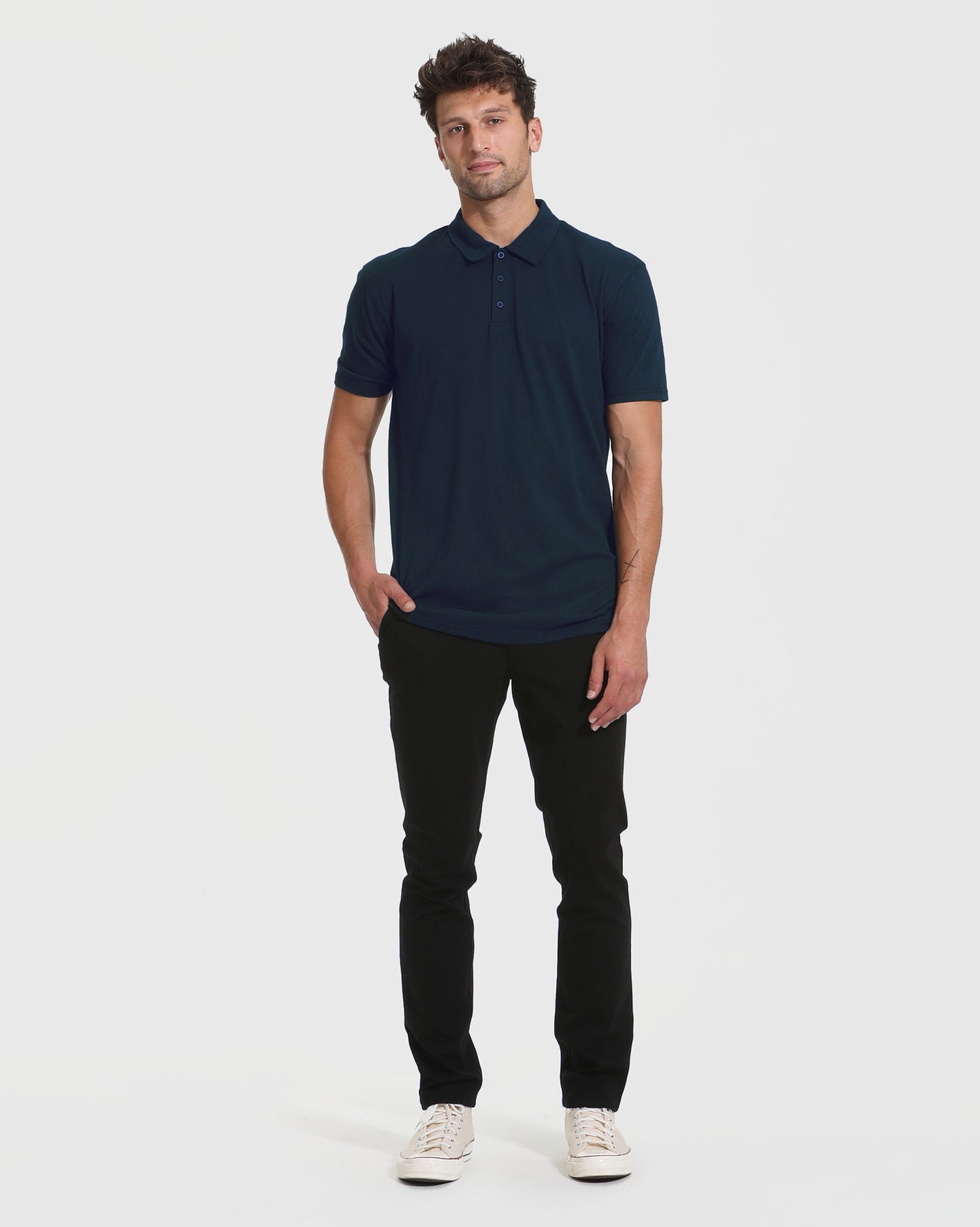 Man wearing Navy Short Sleeve Tall Polo, black pants, canvas sneakers.
