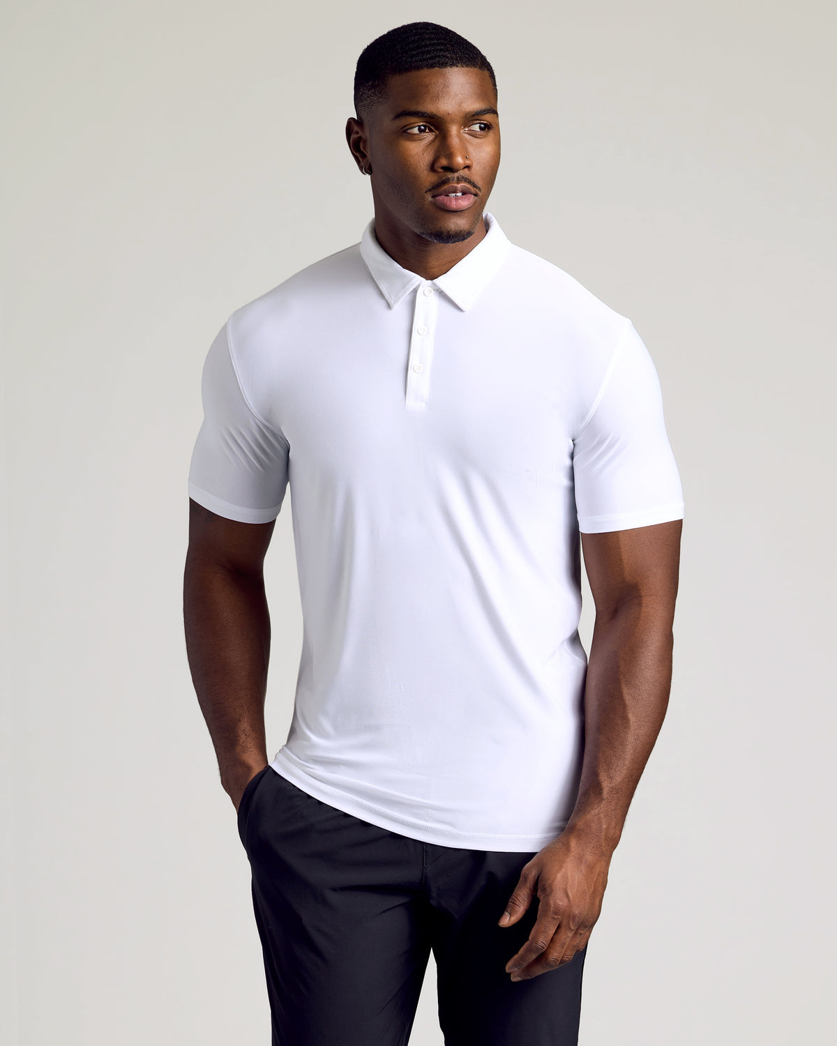 Athletic man wearing a white Tall Active Polo - Men's Performance Stretch Polo Shirt - Moisture Wicking Athletic Fit with short sleeves and a classic collar, paired with black pants.