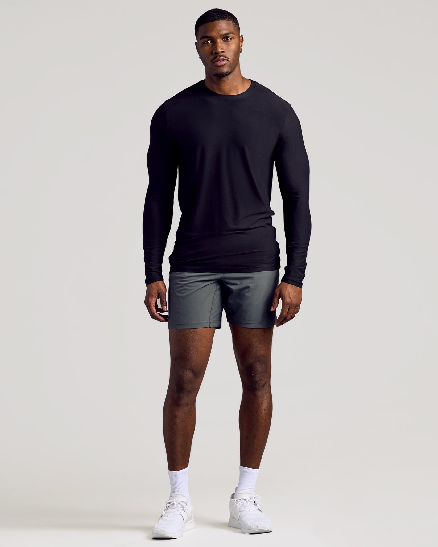 Man wearing Black Long Sleeve Tall Active Crew with gray shorts and sneakers.