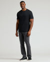 Man wearing a black crew neck t-shirt styled with gray pants and black sneakers, showcasing the Tall Pima Cotton Blend Crew 4-Pack as a comfortable men's basic essential.