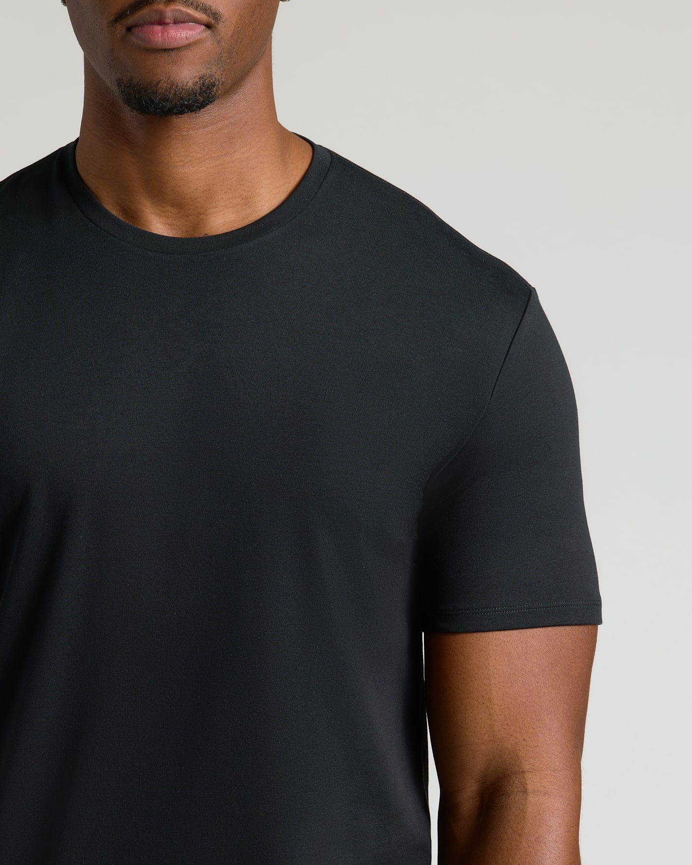 Close-up of a man wearing a black crew neck t-shirt made from a soft, breathable fabric, part of the Tall Pima Cotton Blend Crew 7-Pack men's basics collection.