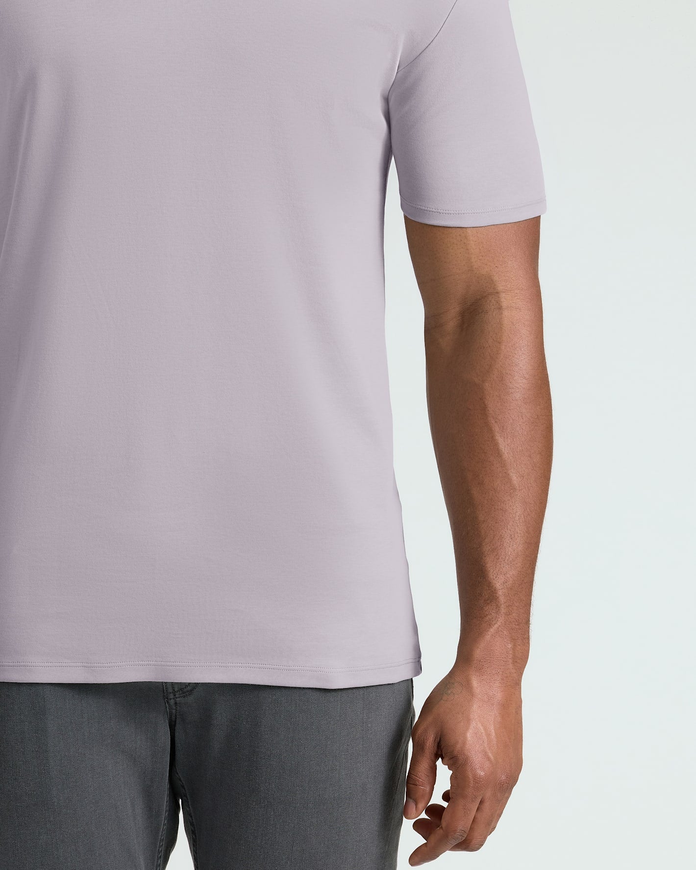 Person wearing a light gray t-shirt and dark gray pants on a white background