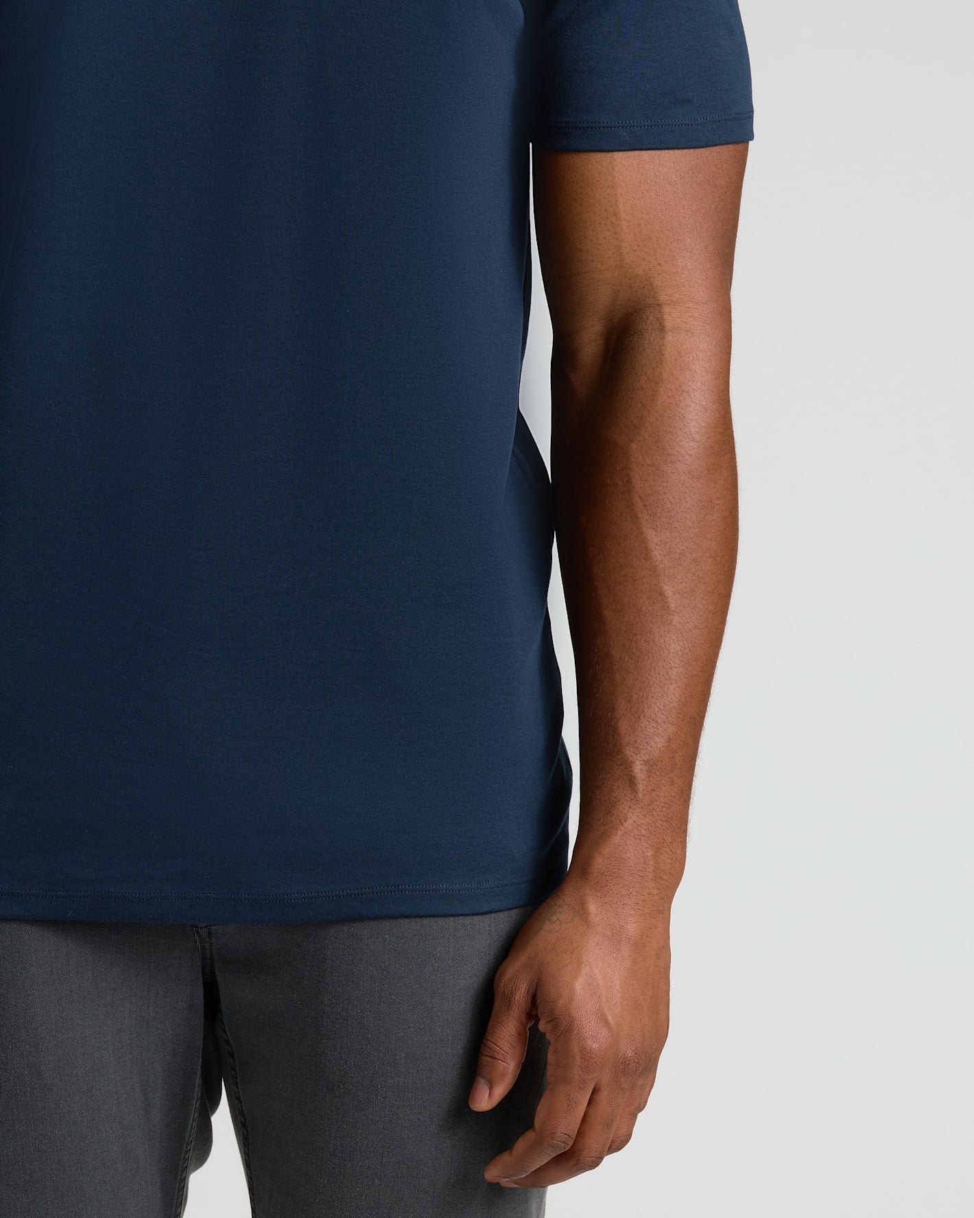 Close-up of a man's torso wearing a navy Navy Tall Pima Cotton Blend Crew shirt paired with dark grey pants, showcasing the smooth fabric and comfortable fit of this men's basic.