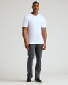 Man wearing a white Tall Pima Cotton Blend Crew 4-Pack t-shirt paired with dark gray pants and black sneakers, showcasing a clean and modern men's basics look.