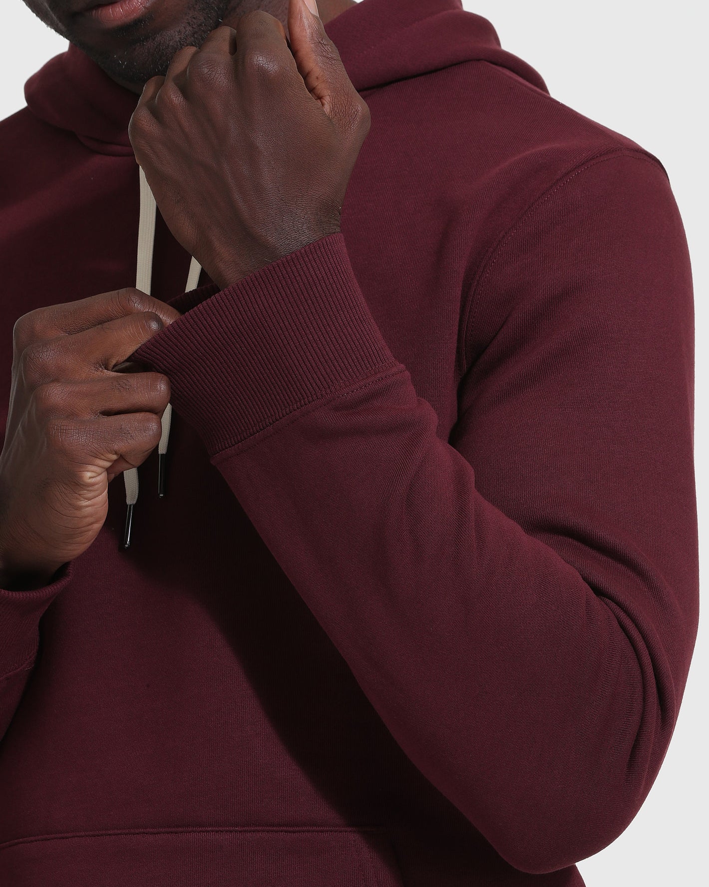 Adjusting the Mahogany Fleece French Terry Pullover Hoodie’s cuff and drawstrings.