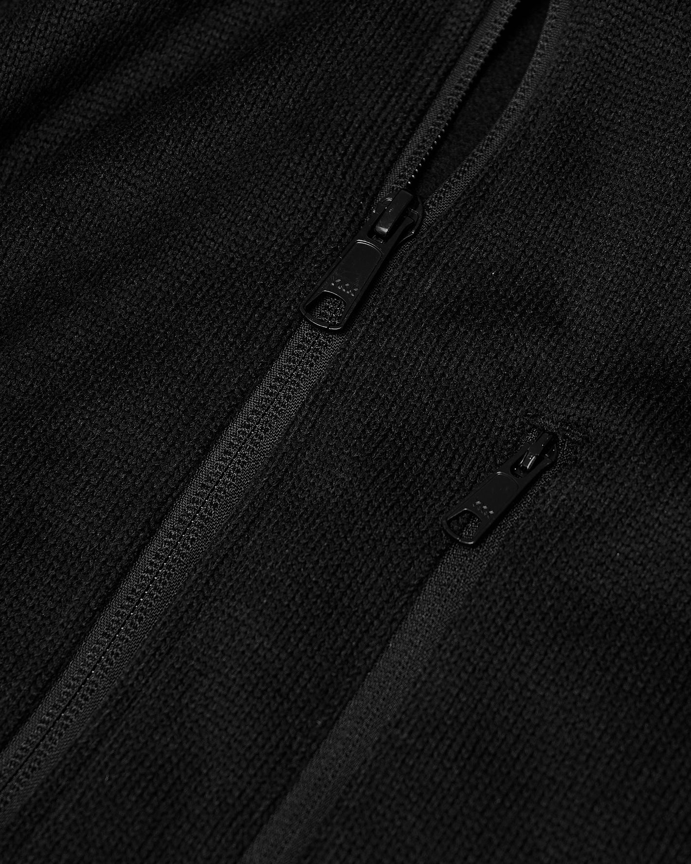 Black Sweater Fleece Jacket close-up showing textured fabric with zippers.