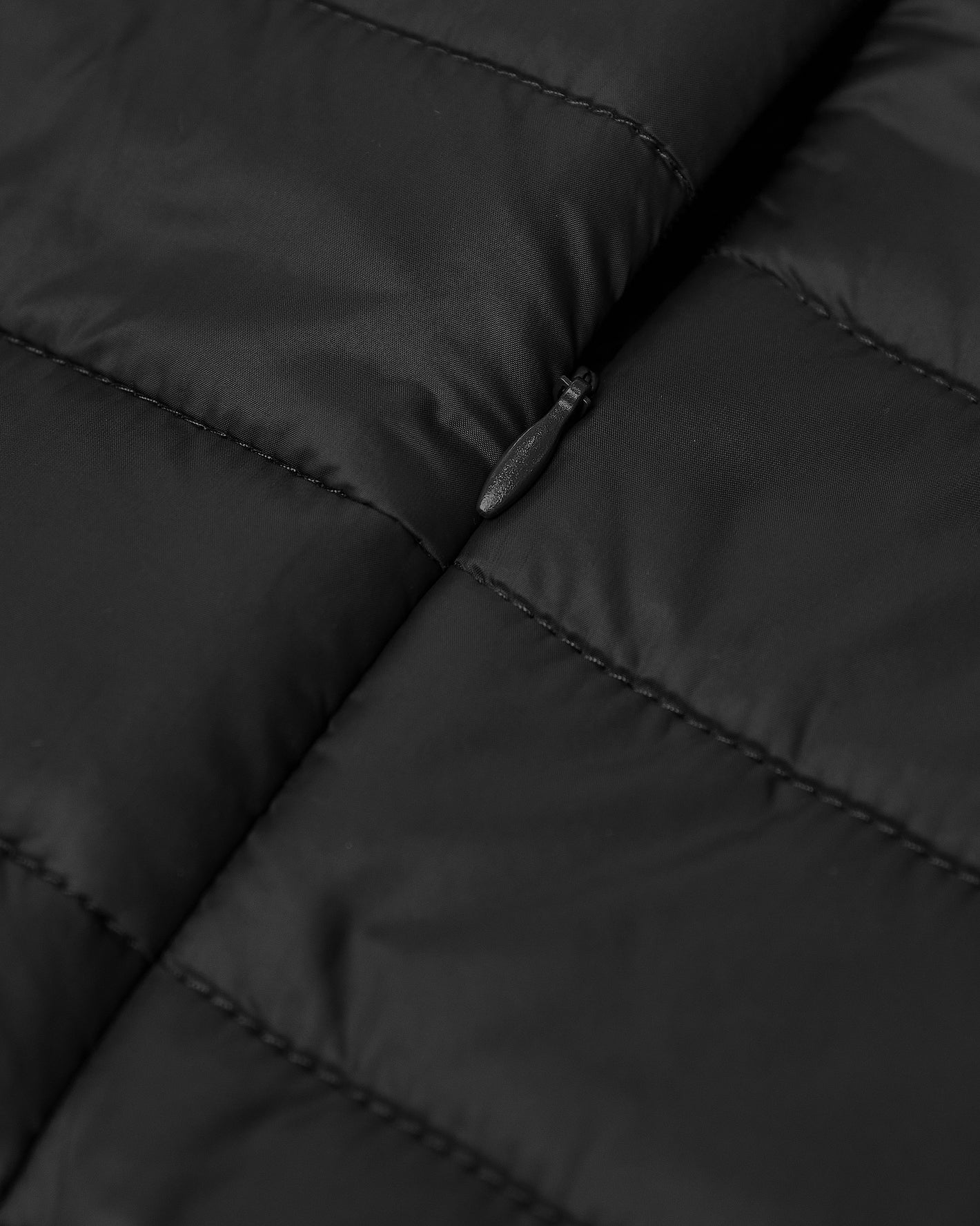 Black Puffer Jacket close-up with quilted baffles and zipper pull.