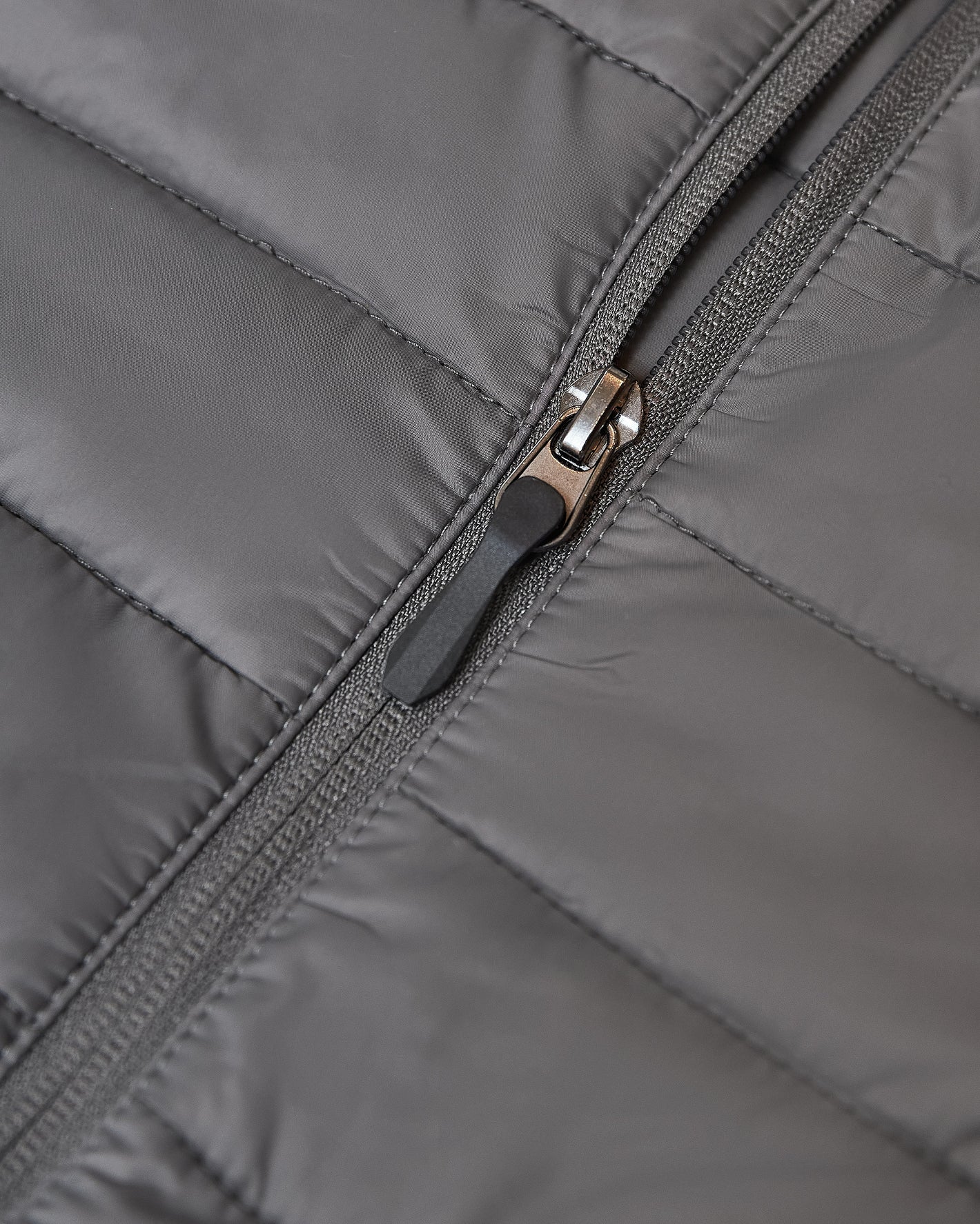 Gunmetal Puffer Jacket's zipper on quilted fabric.