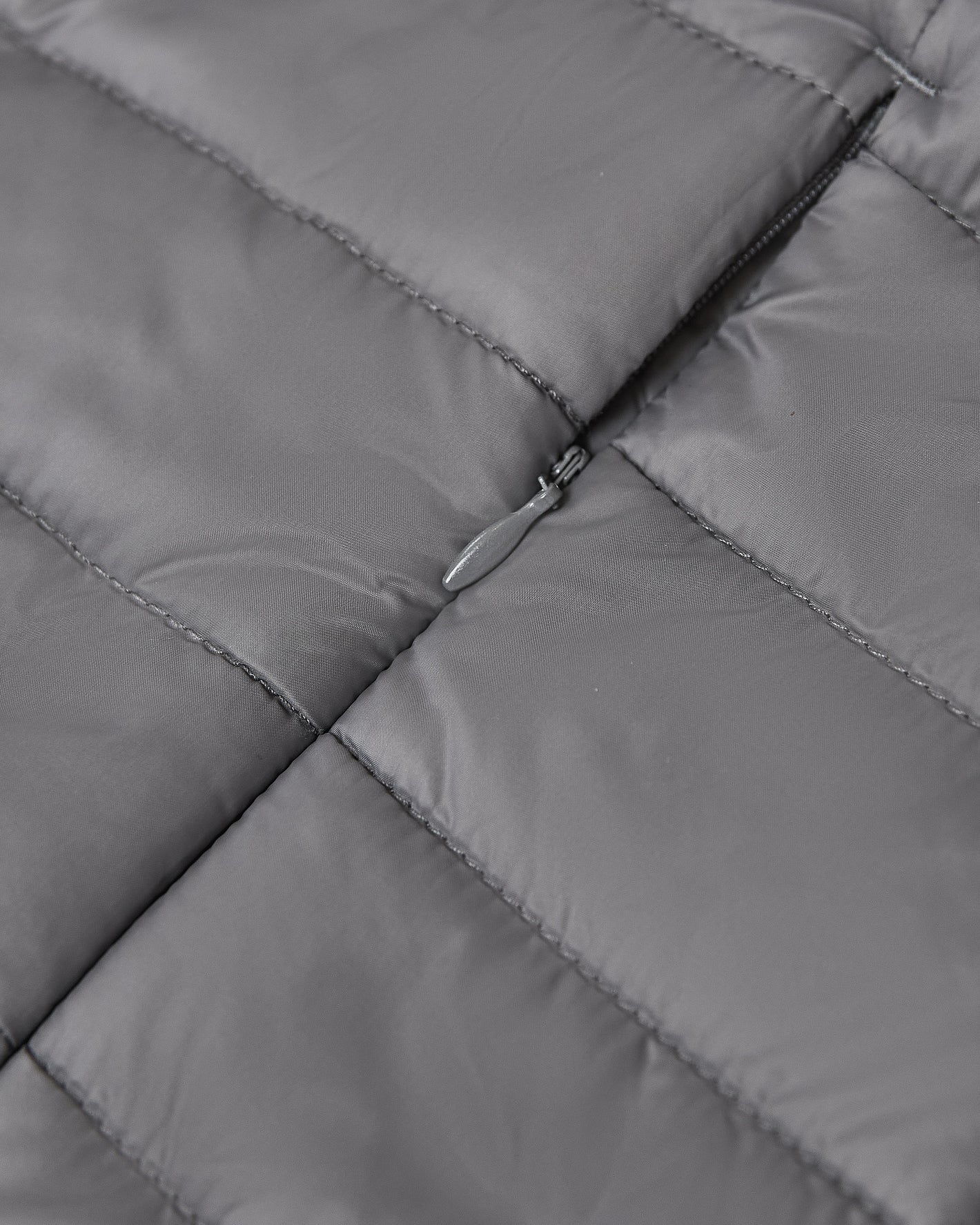 Gunmetal Puffer Jacket, close-up of grey quilted fabric with zipper.