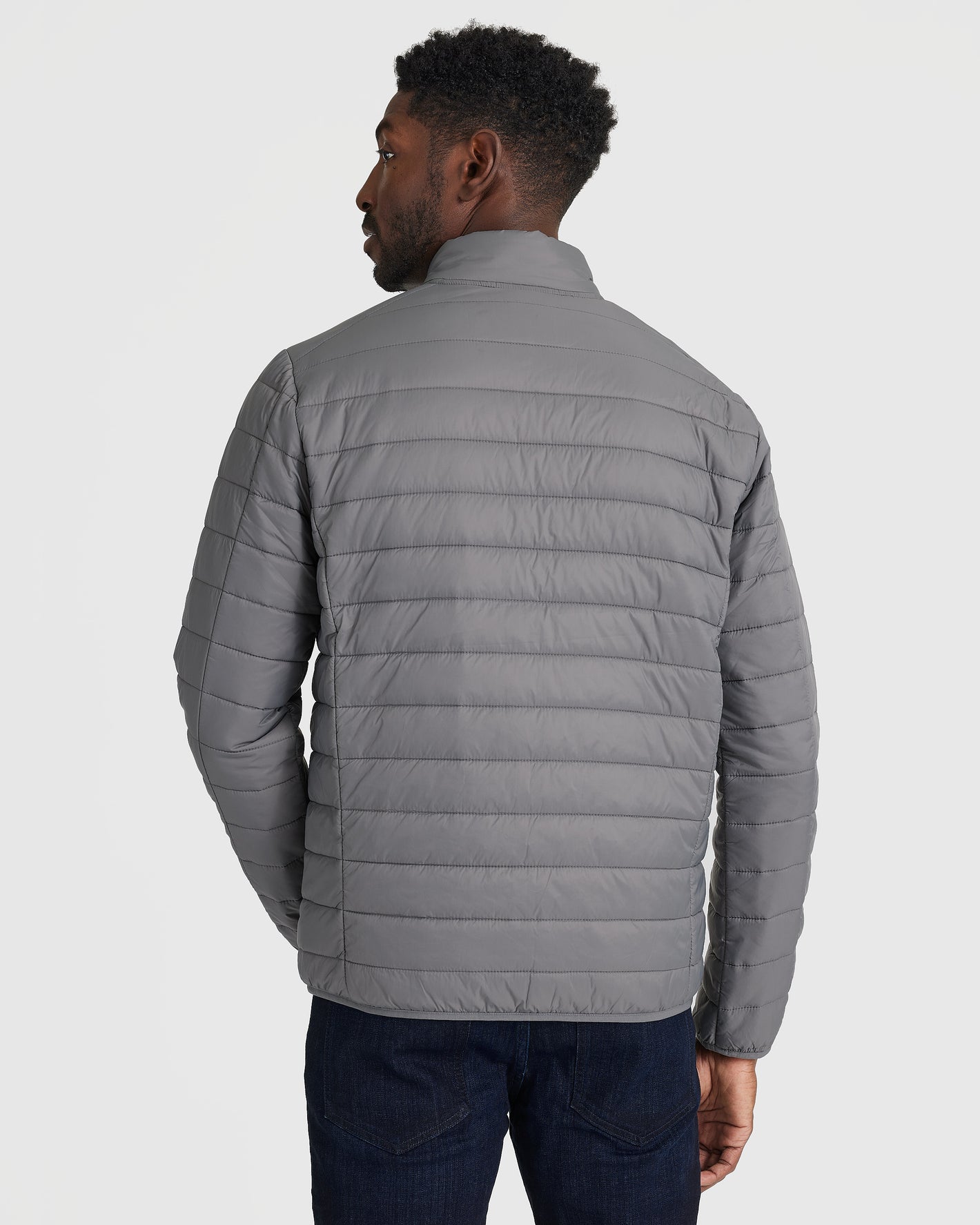 Man wearing Gunmetal Puffer Jacket with horizontal stitching, seen from behind.