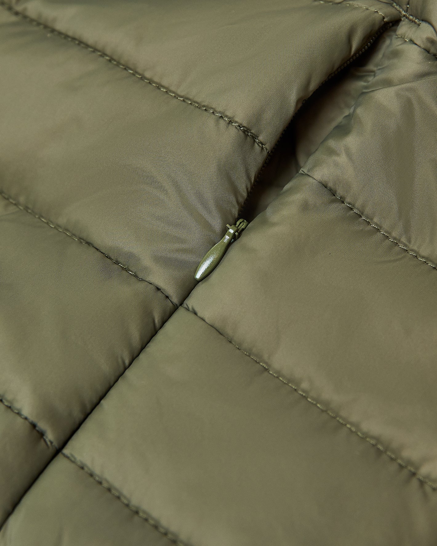 Military Green Puffer Jacket showing quilted fabric and zipper pocket.