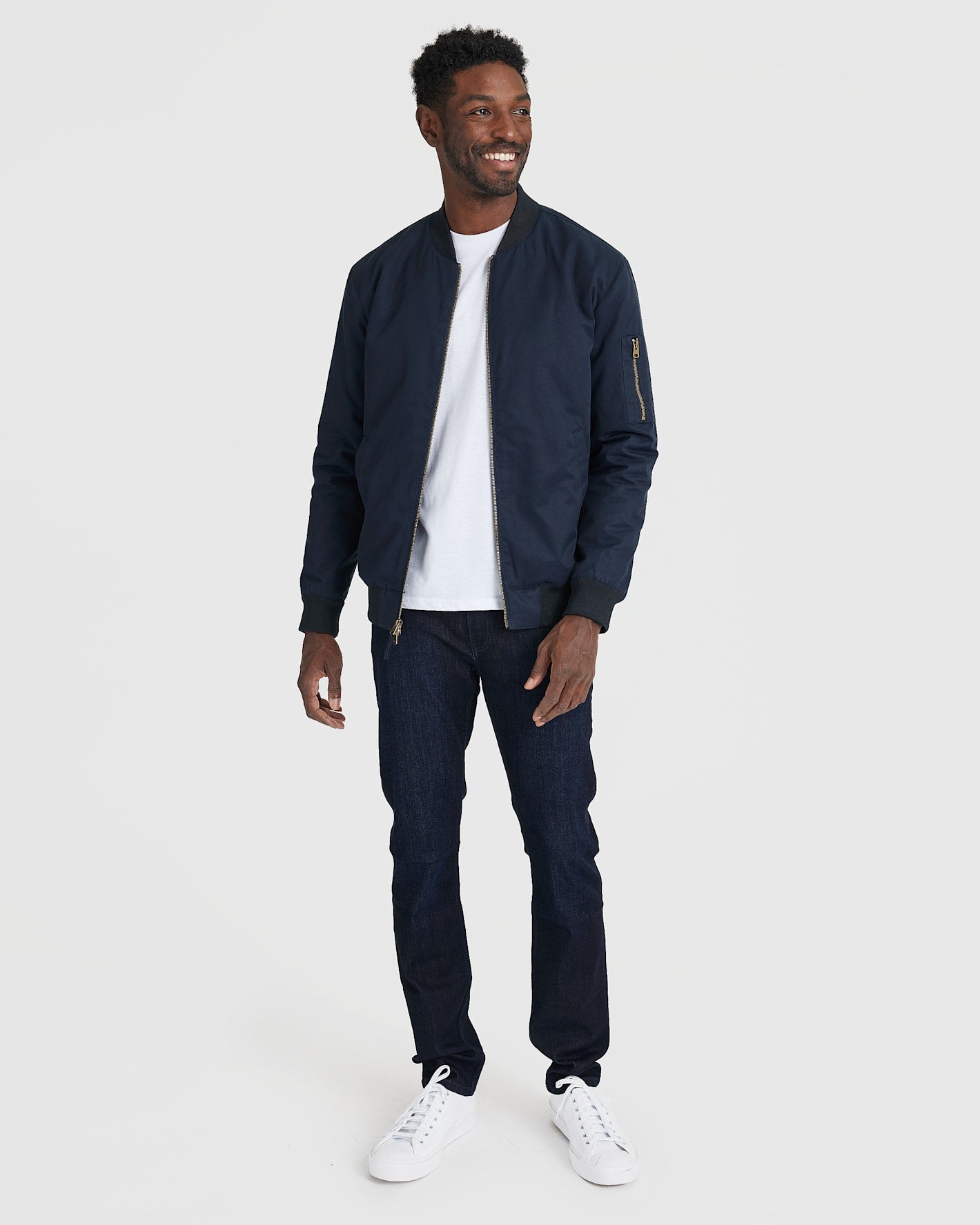 Man modeling Navy Bomber Jacket with jeans and sneakers.