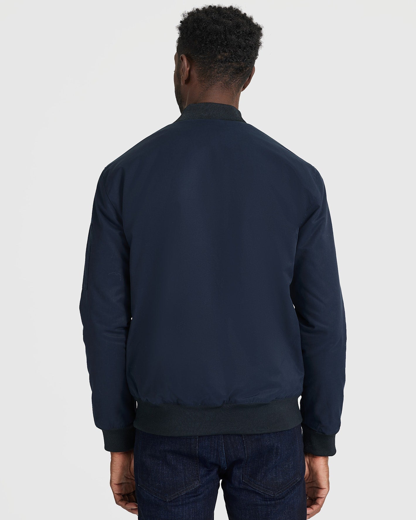 Man wearing Navy Bomber Jacket, showcasing back view.