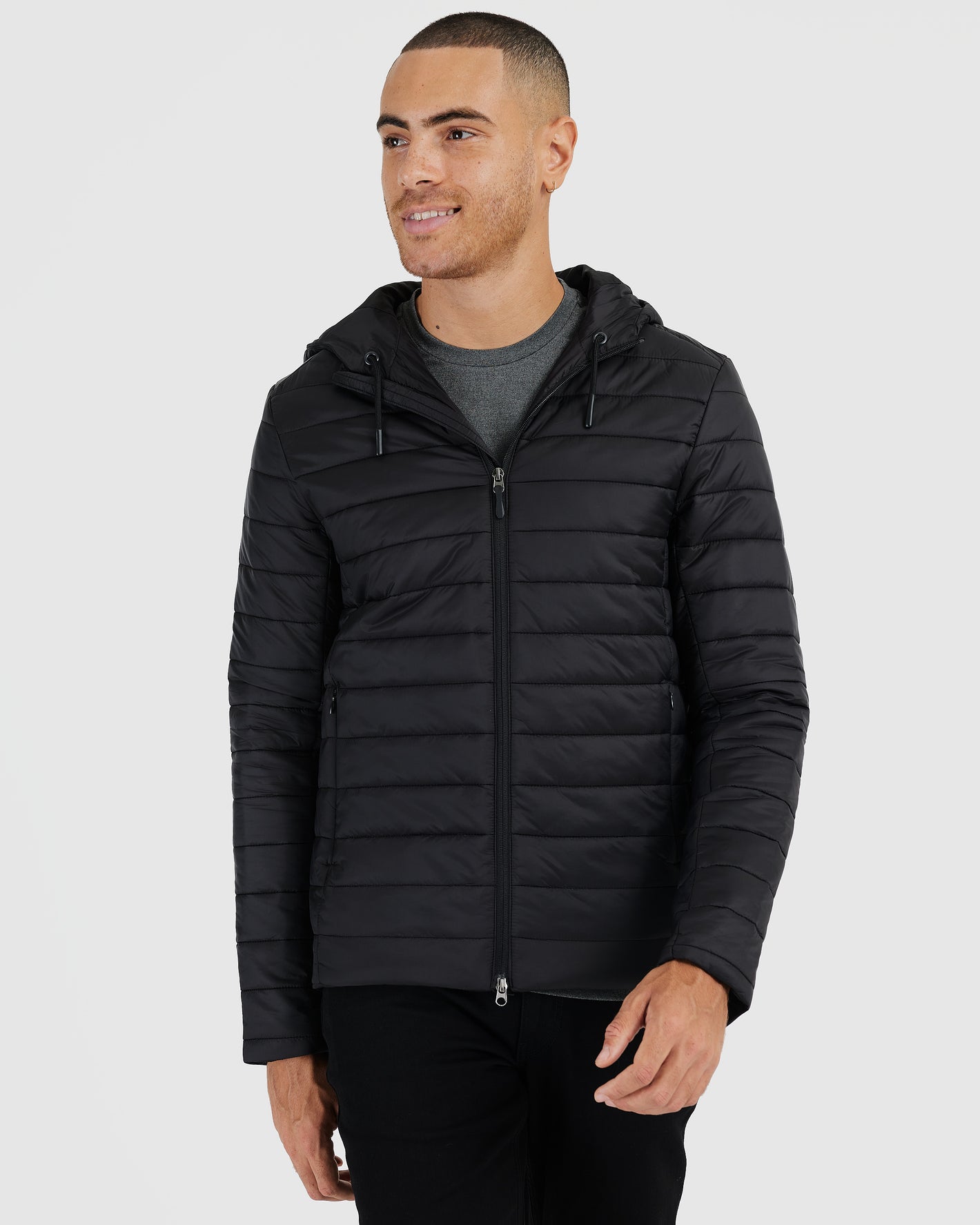 Black Hooded Puffer Jacket on male model, featuring zippered pockets and drawcord hood.