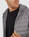 Man wearing Gunmetal Hooded Puffer Jacket, holding zipper near chest.