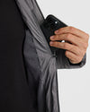 Inserting smartphone into Gunmetal Hooded Puffer Jacket's zippered interior pocket.