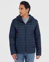 Man wearing Navy Hooded Puffer Jacket over gray sweatshirt, blue jeans.