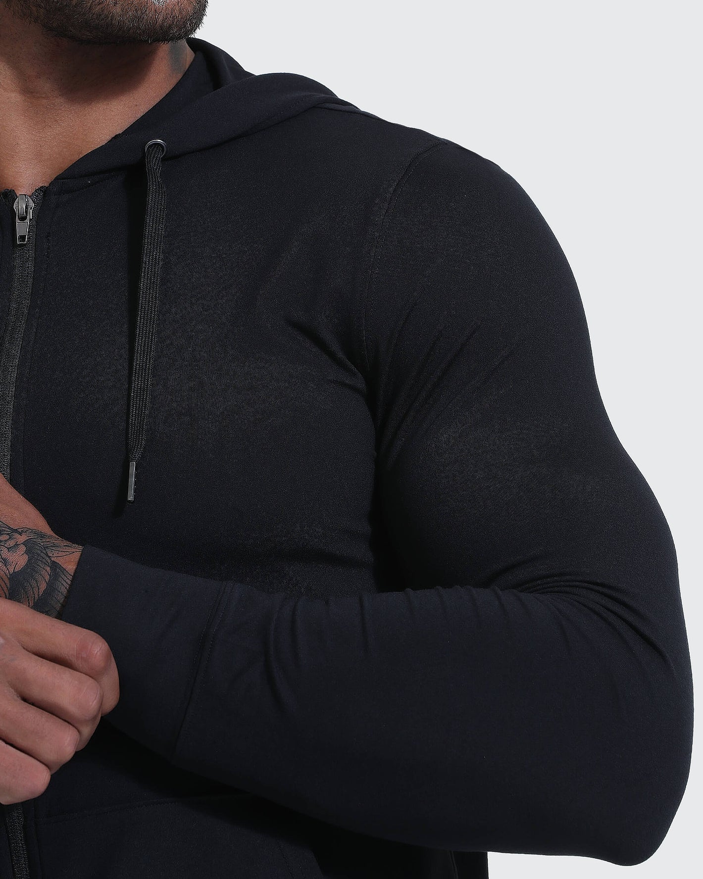 Muscular person wearing Black Active Comfort Full Zip Hoodie, adjusting sleeve.