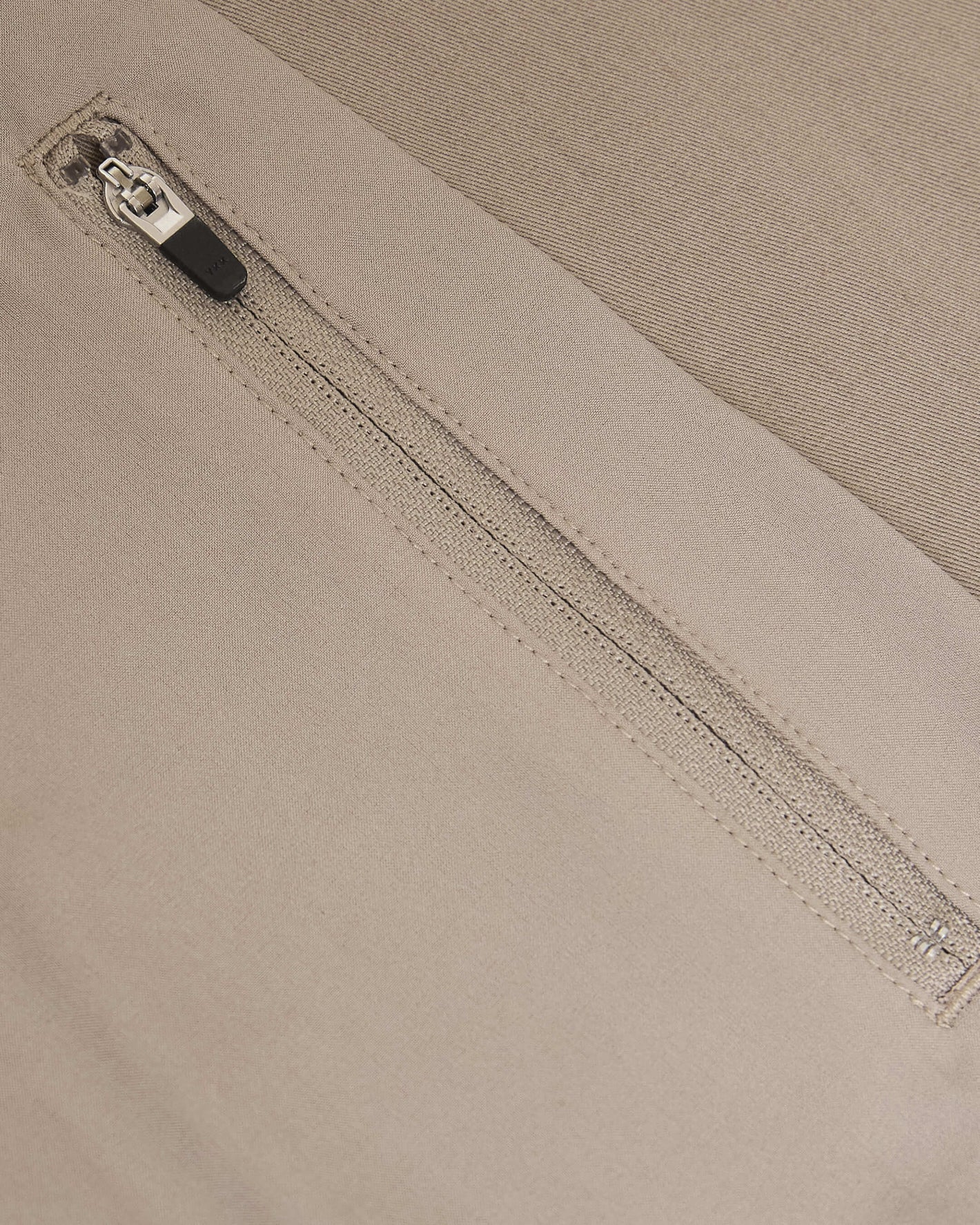 Khaki Coaches Jacket zipper detail on beige twill fabric.