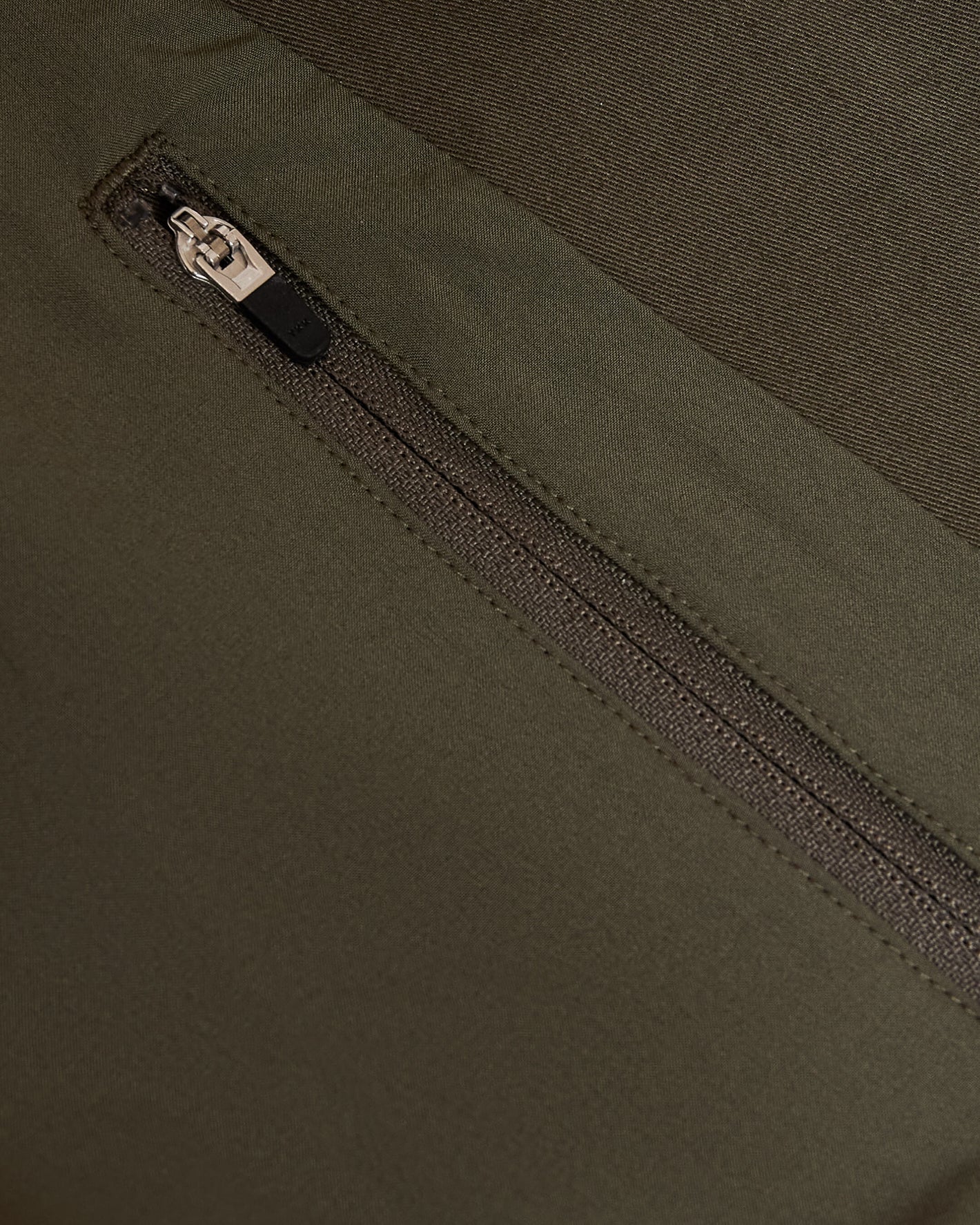 Zippered pocket on Military Green Coaches Jacket, showcasing durable fabric.