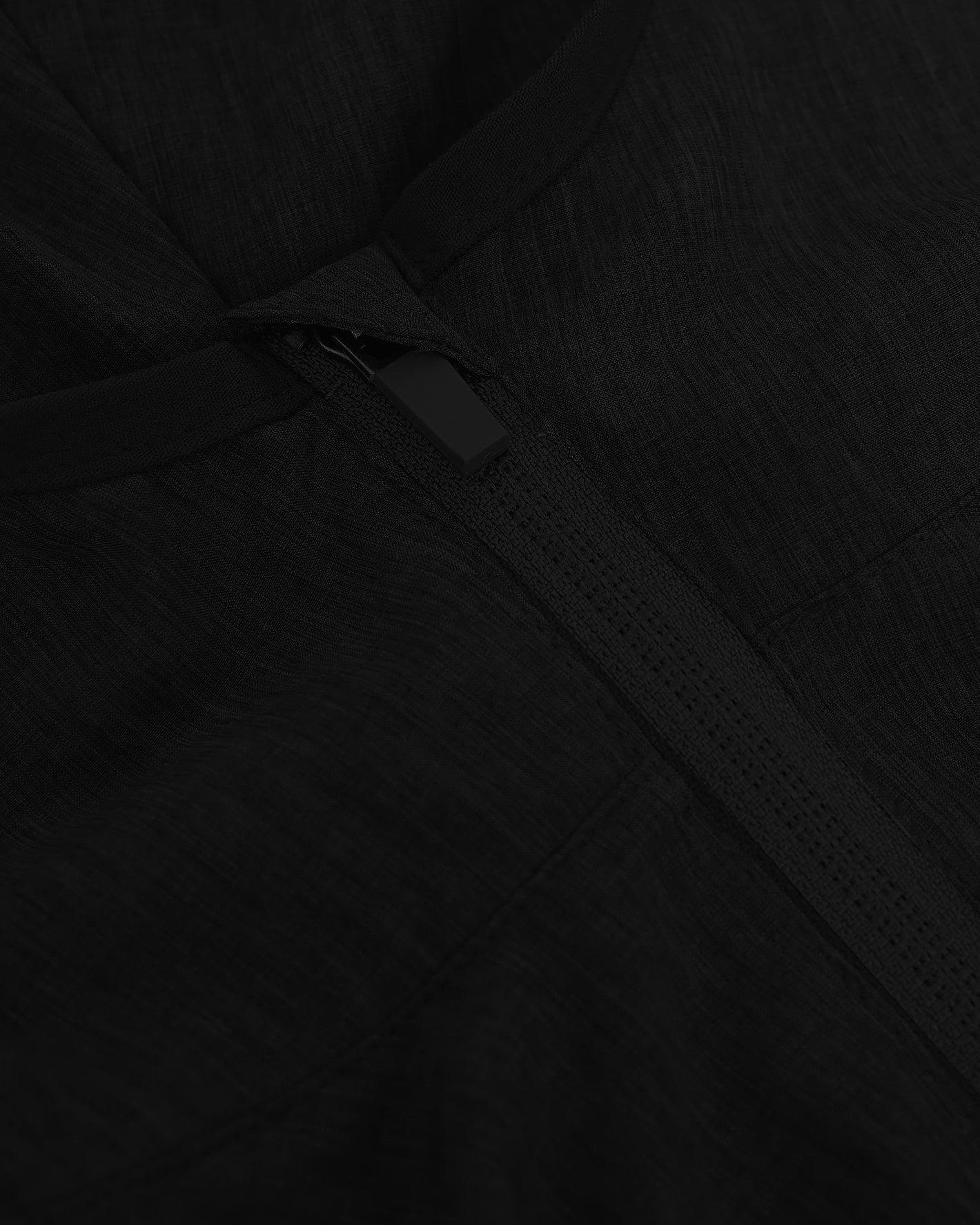 Black Active Shell Jacket showing zipper detail and surrounding fabric texture.