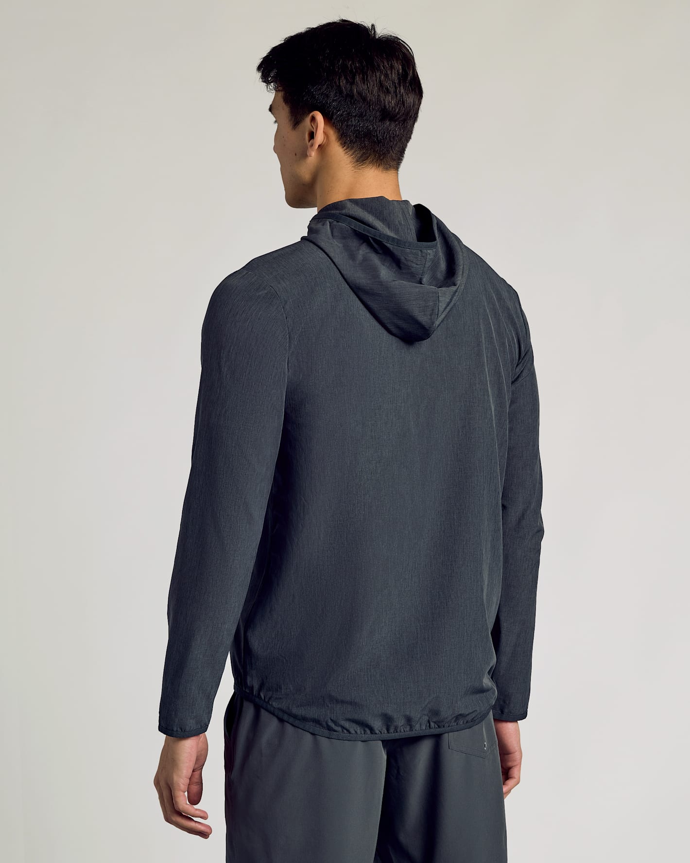 Man wearing Charcoal Heather Gray Active Shell Jacket, hood down, back view.