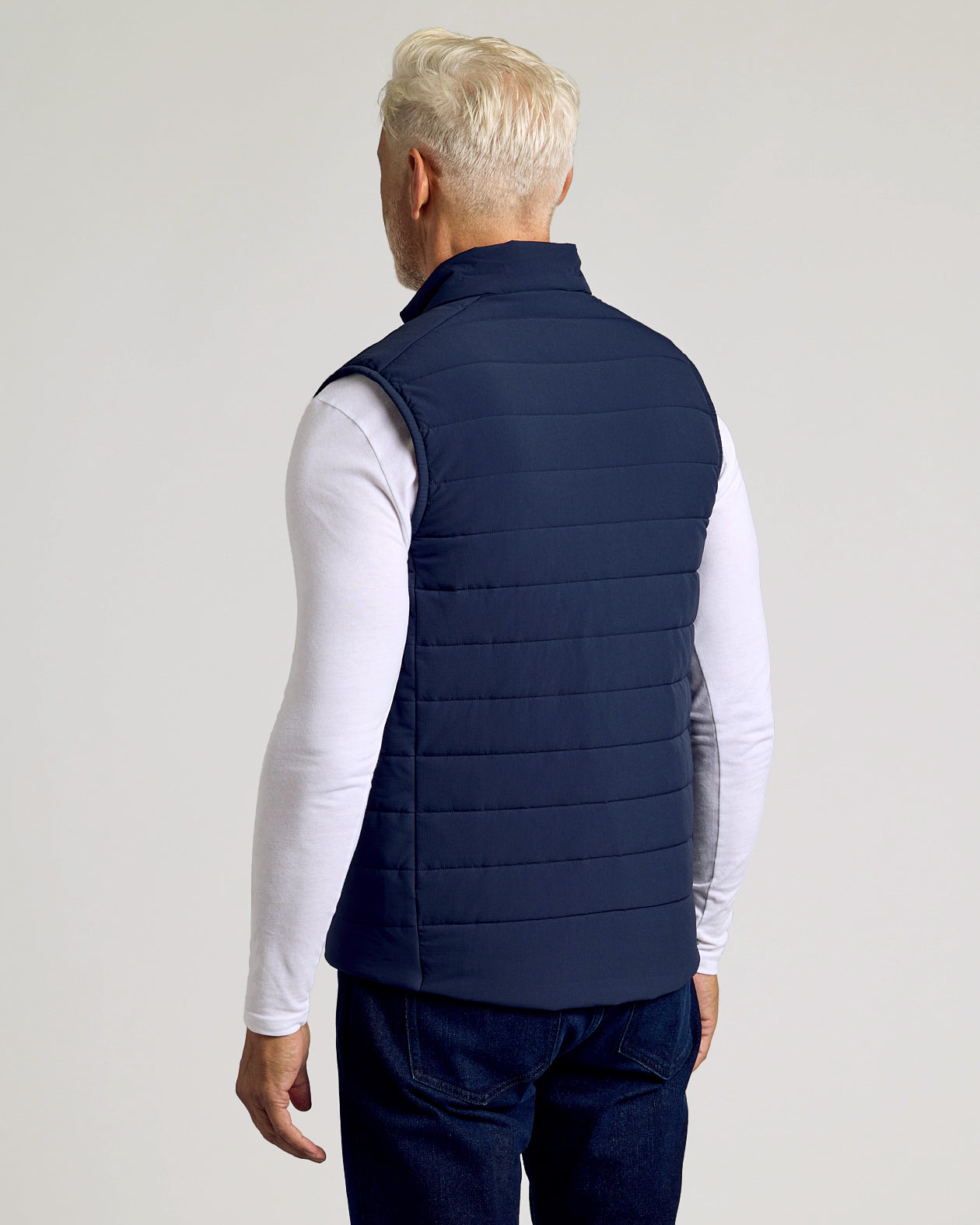 Man wearing Navy Puffer Vest over long-sleeve T-shirt and jeans.