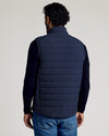 Man wearing a Navy Puffer Vest from the back, paired with a dark long-sleeve shirt and blue jeans, showcasing the vest’s quilted design and casual fit.
