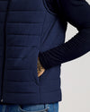 Close-up of a person wearing a Navy Puffer Vest over a long-sleeve black shirt with their hand in the vest pocket, showing quilted stitching and casual style.