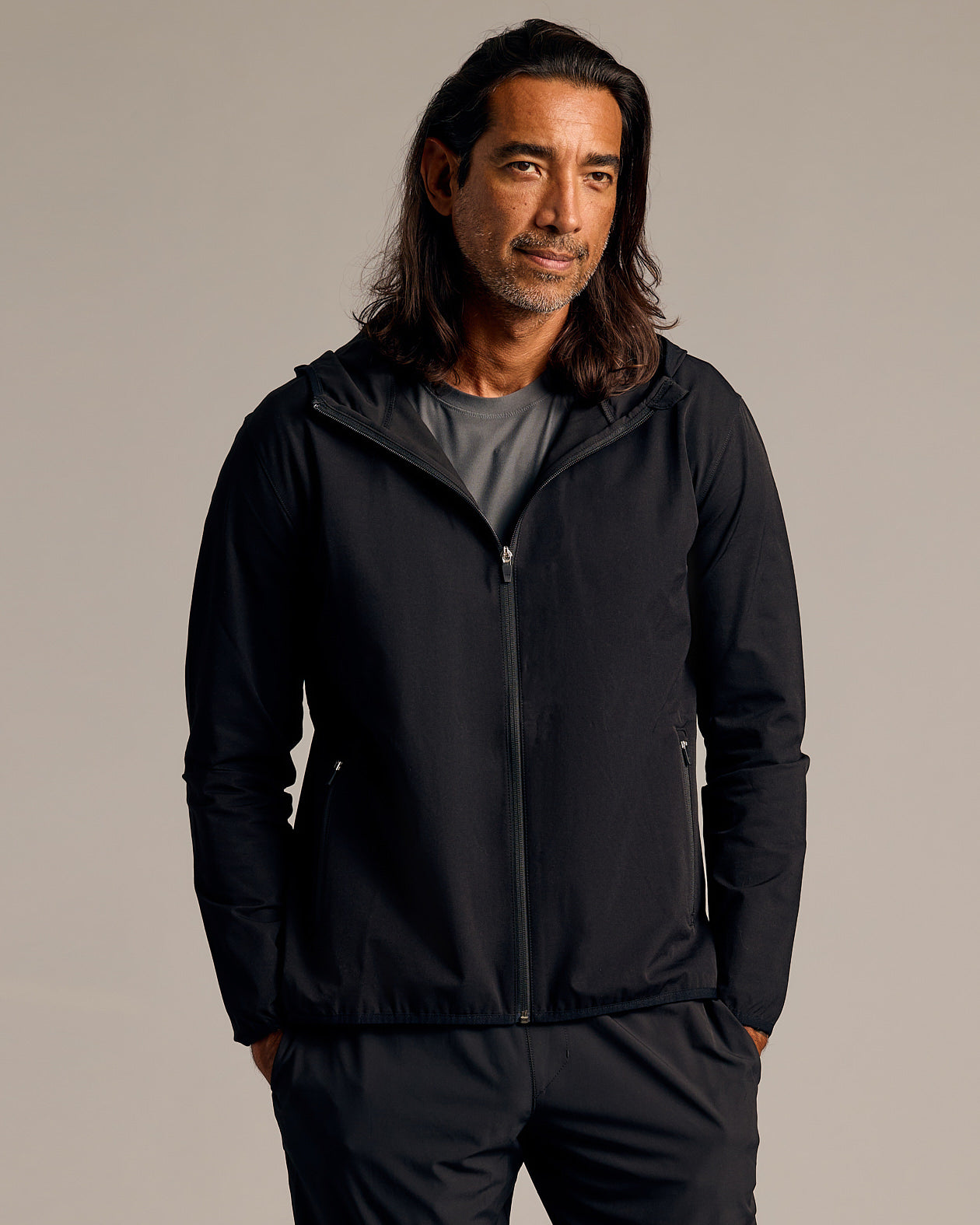 Man in Black Tech Windbreaker with hood and zip pockets.