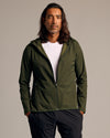 Olive Tech Windbreaker on man, hands in pockets, studio setting.
