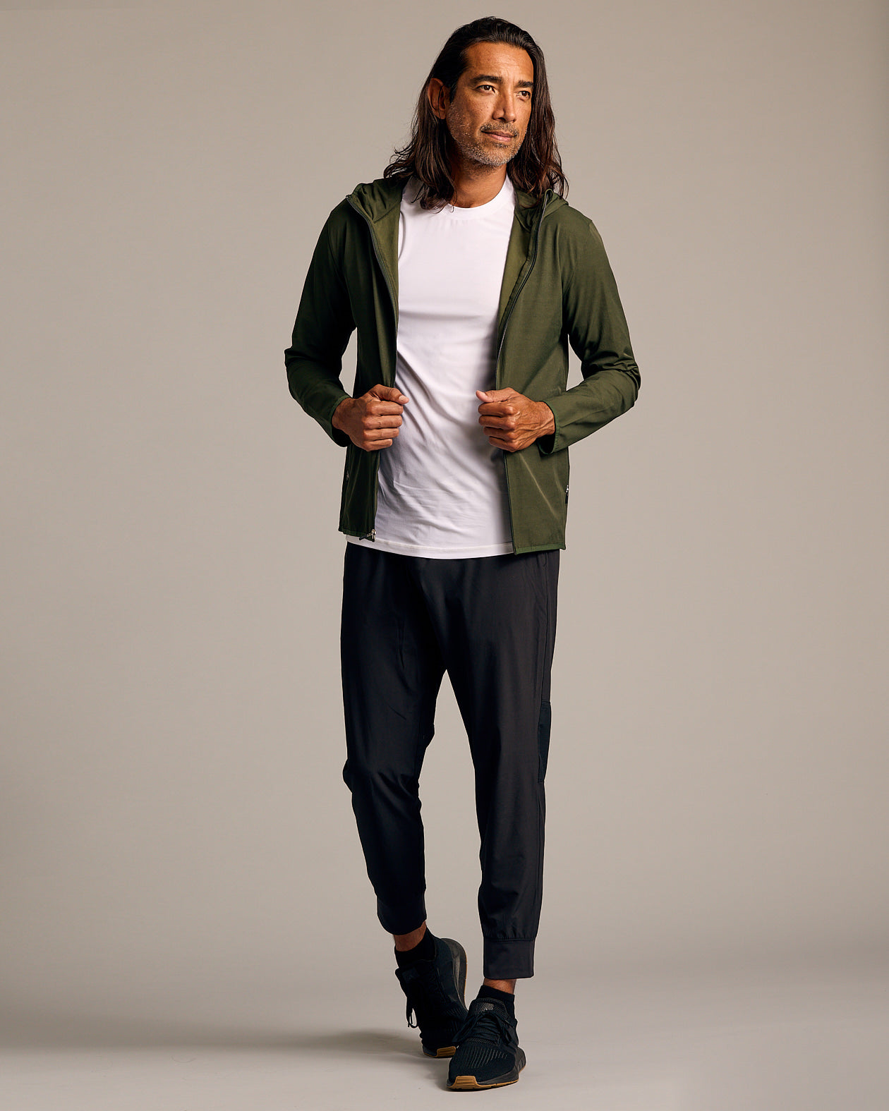 Man wearing Olive Tech Windbreaker, unzipped over white T-shirt.