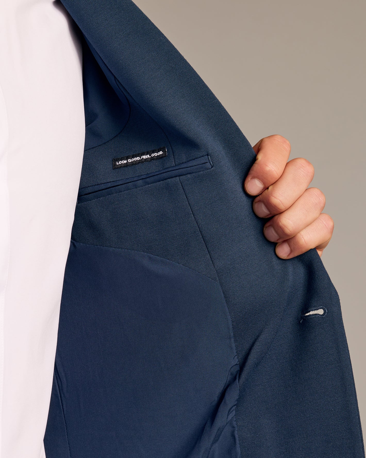 Person holding open Navy Comfort Knit Blazer, showing interior lining and label.