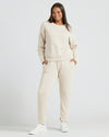 Woman in Womens Oatmeal Slouch Pullover Crew smiling, hands in pockets.