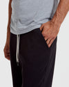 Man wearing a gray t-shirt and black pants on a white background