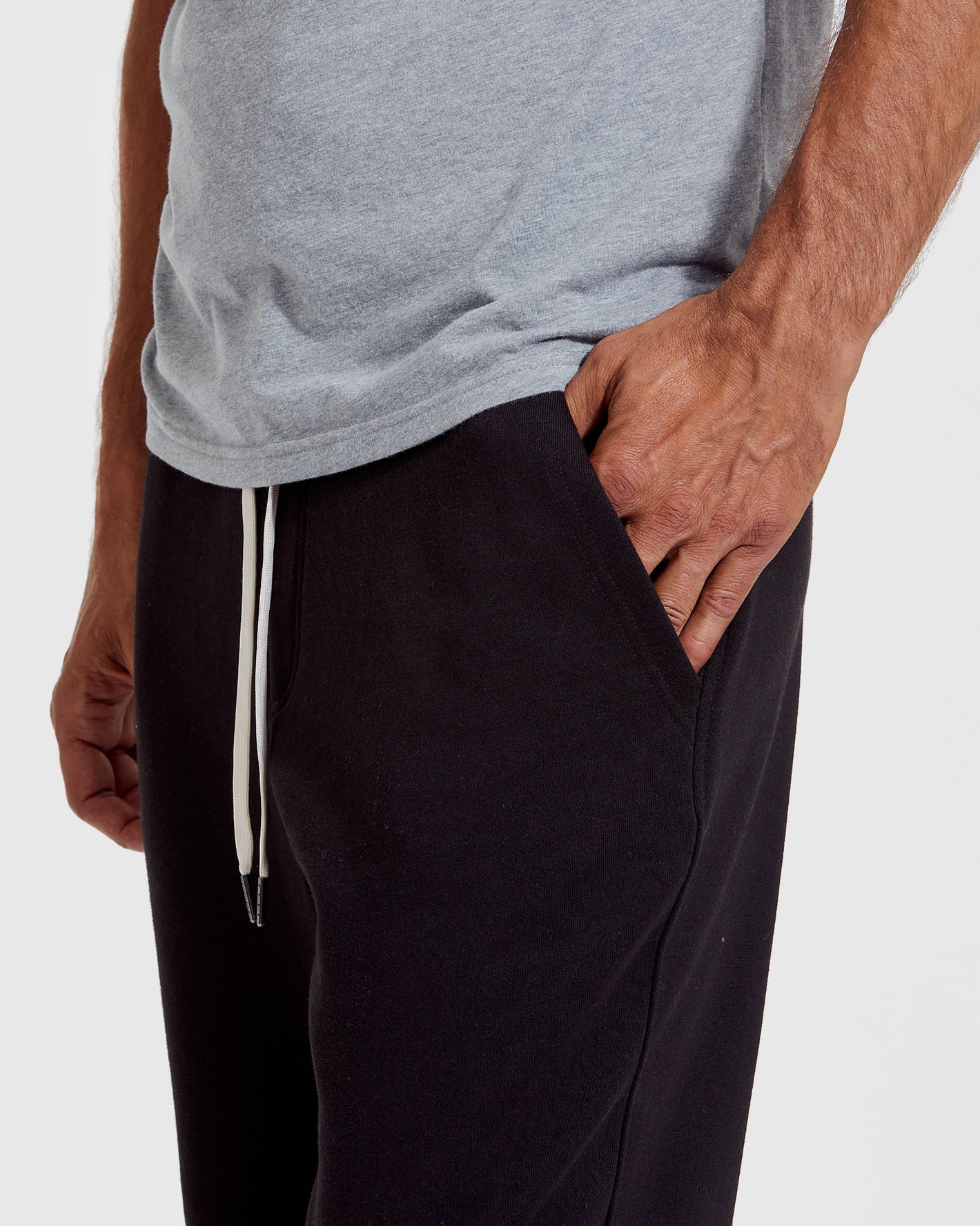 Man wearing a gray t-shirt and black pants on a white background