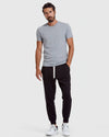 Man wearing a gray t-shirt and black pants on a white background
